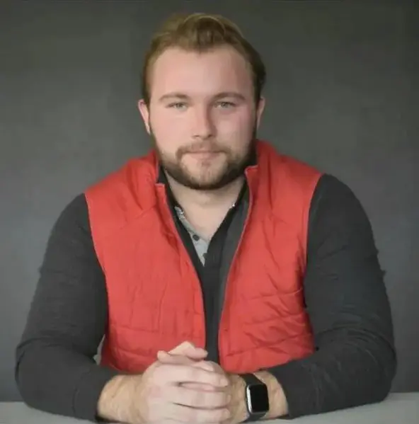 A man in a red vest sitting at a table.